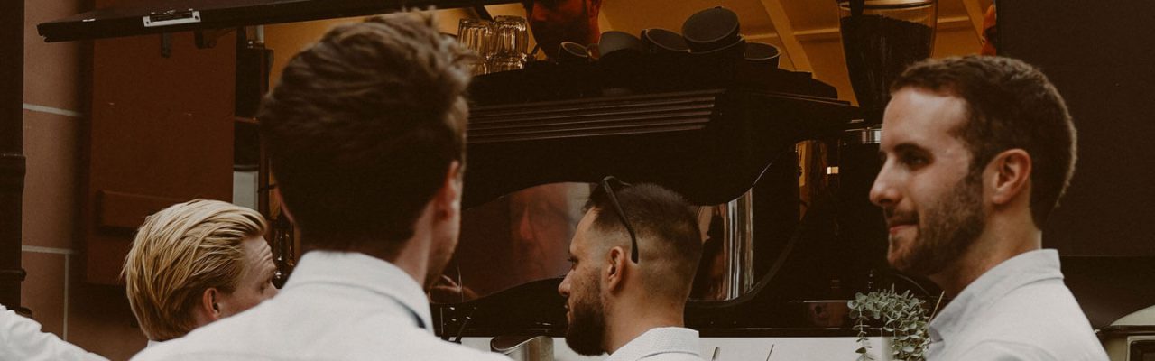 Ein paar schick gekleidete Menschen stehen vor der Kaffee-Ape.