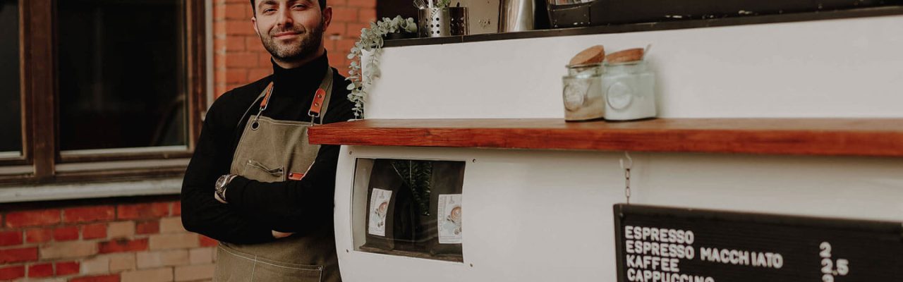 Der Barista steht neben seiner Kaffee-Ape. mobiles Kaffeecatering